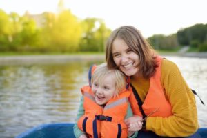 Mother and son practicing safe boating on a lake