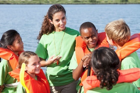 Young woman educating group of children on safe boating procedures 