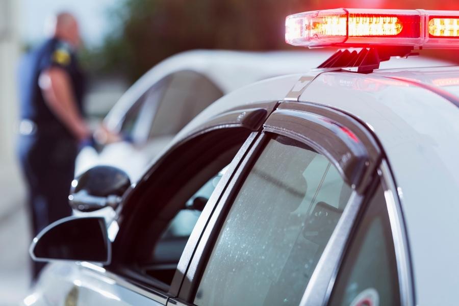 A police car flashing red lights to pull over an impaired driver, before he causes an accident.